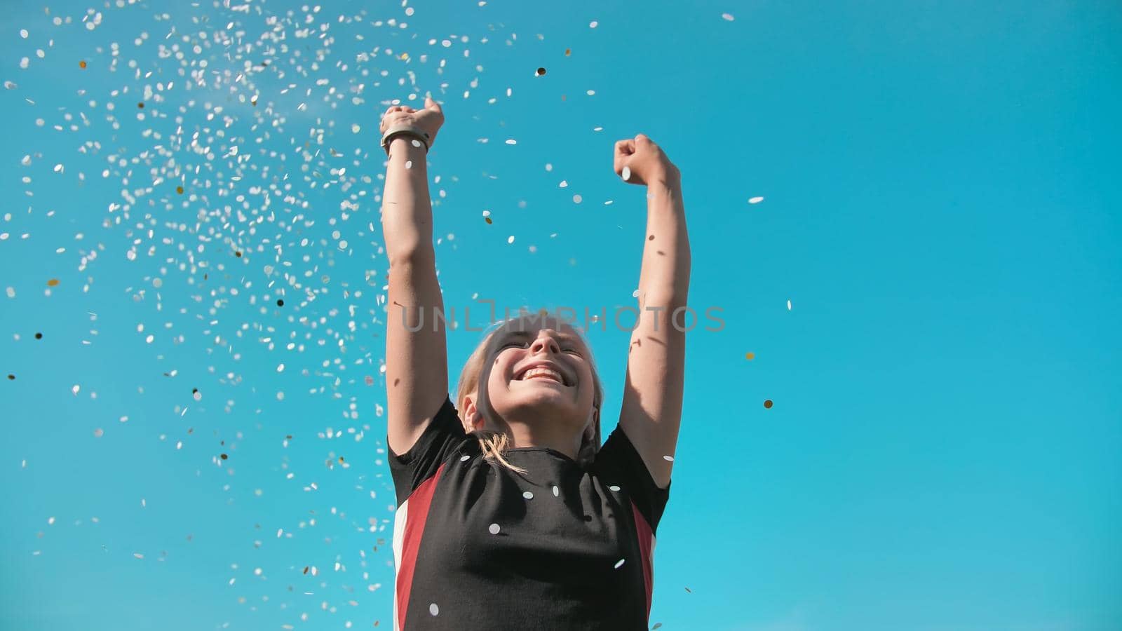 Success concept. Teen girl throws a multi-colored confetti into the blue sky