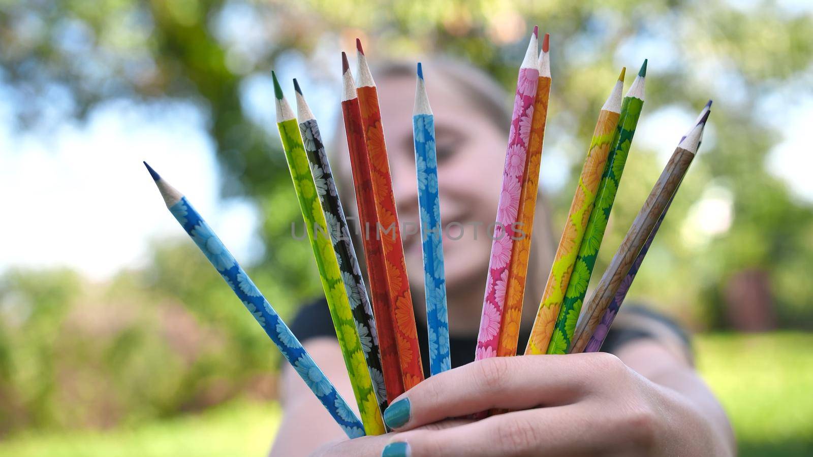 Group of multicolored pencils in young girl's hand. by DovidPro