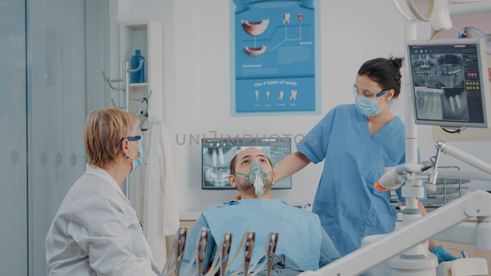 Dentistry nurse doing anesthesia with oxygen mask on patient, preparing to do drill procedure to cure toothache. Dentist using dental tools and anesthesic for surgery in stomatological office.