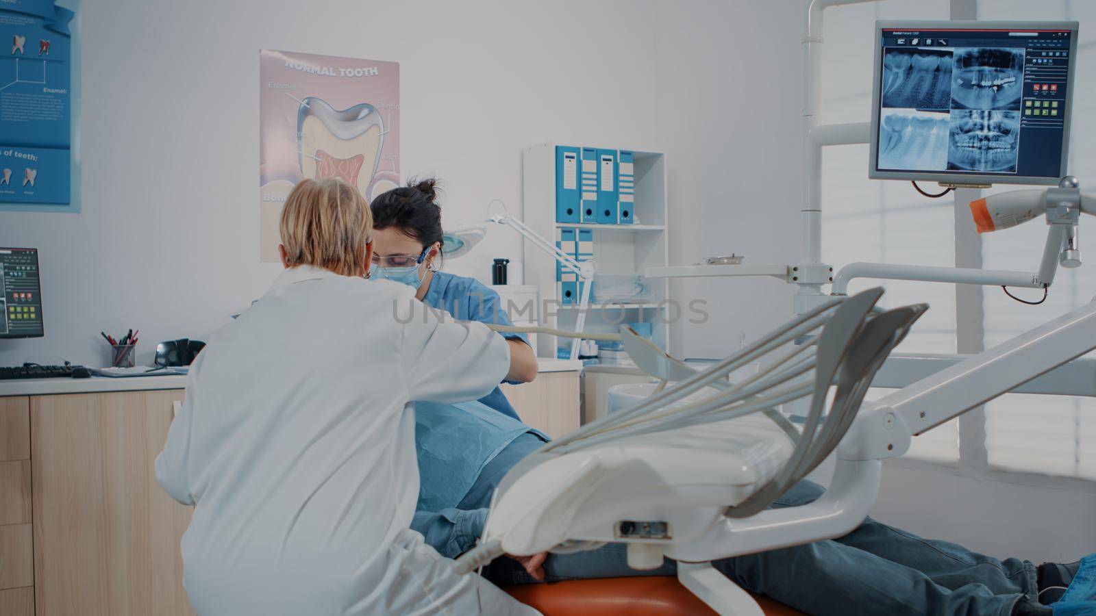 Woman dentist using instrument to do drill procedure, treating patient with toothache. Stomatologist examining denture with dental tools for oral care inspection. Dentistry inspection