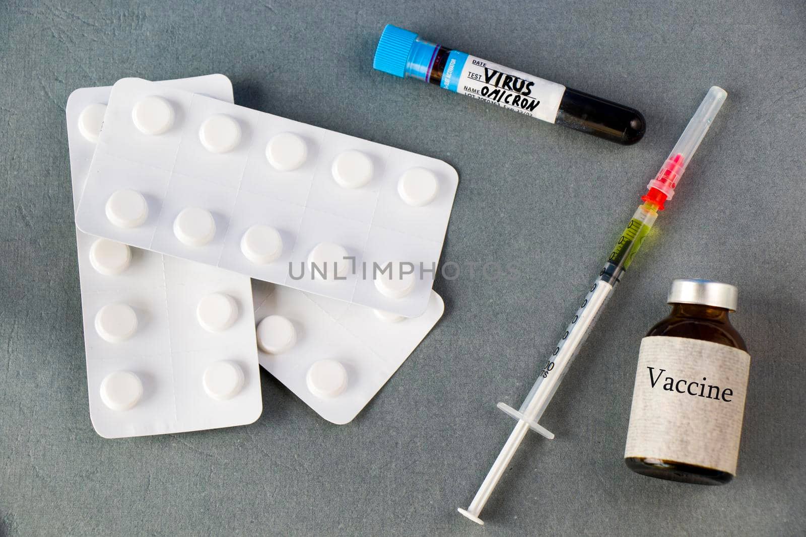 Omicron, corona virus variation.Vaccine ampule, needle, drugs and blood tube on the gray background, virus vaccine