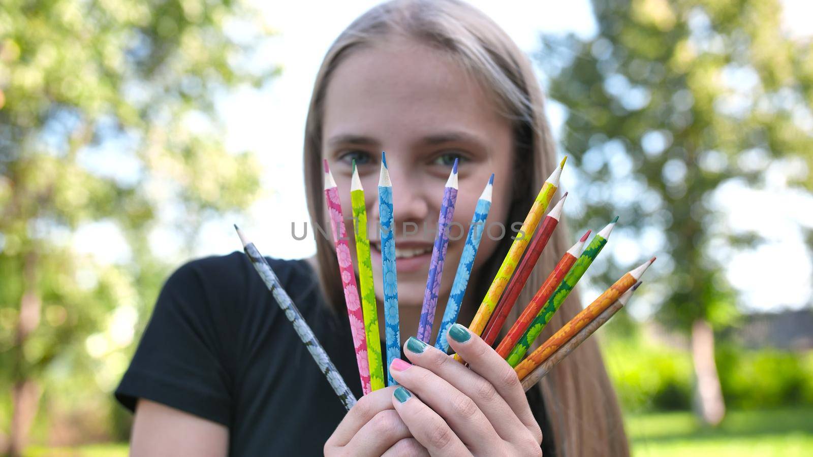 Group of multicolored pencils in young girl's hand. by DovidPro