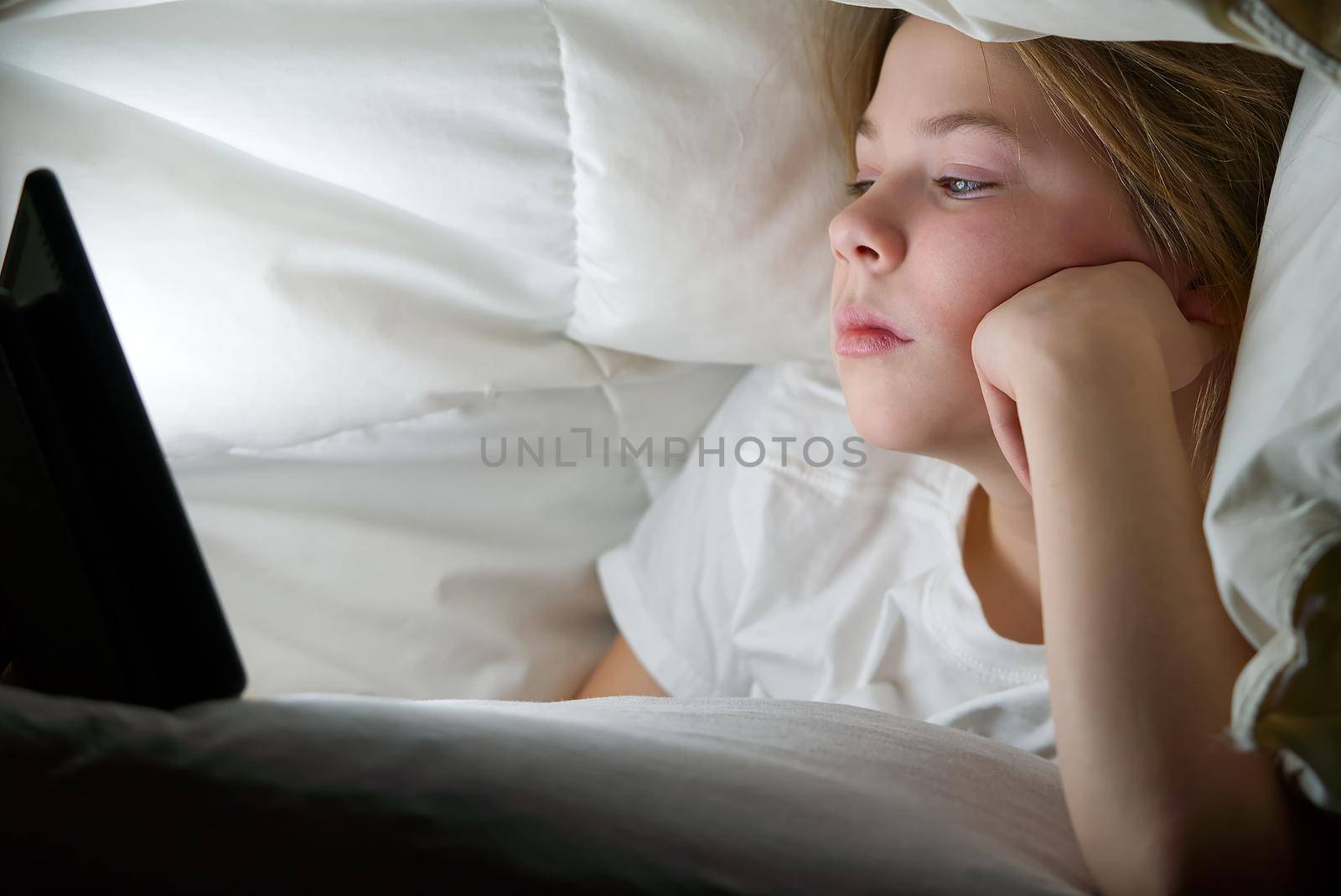 Portrait of girl with tablet under blanket at night. Gadget night. Social media addiction. Online communication. by PhotoTime