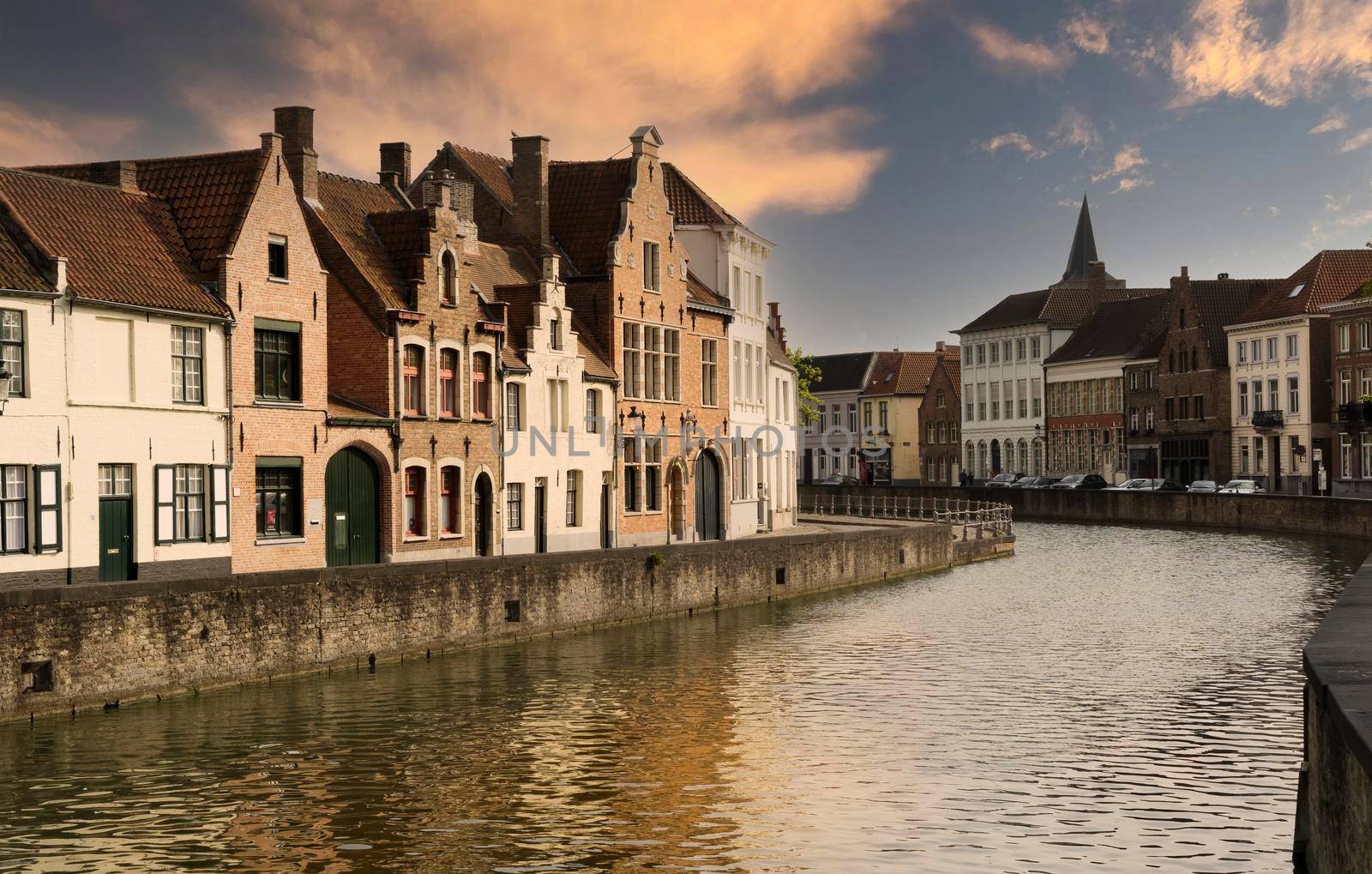 Street in the medieval Belgian city of Bruges at sunset and crossed by one of the canals.