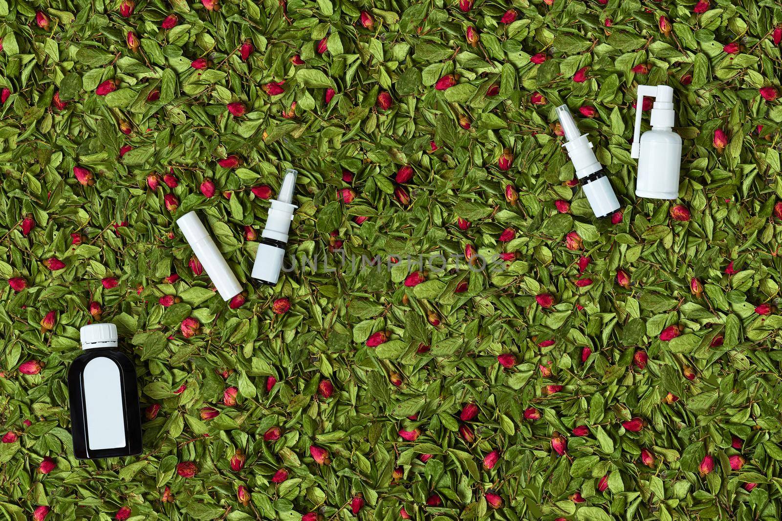 Bottle of cough syrup, two vials of nasal drops, hygienic lipstick and spray with no logo on dried rose buds and leaves background. Packaging of medicinal products, branding area. Copy space, mock up