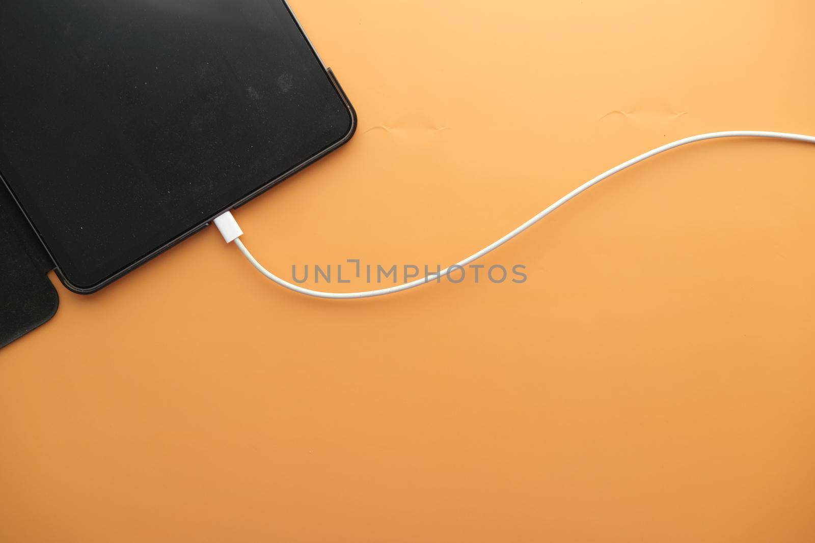 charging smart phone with a cable on color background .