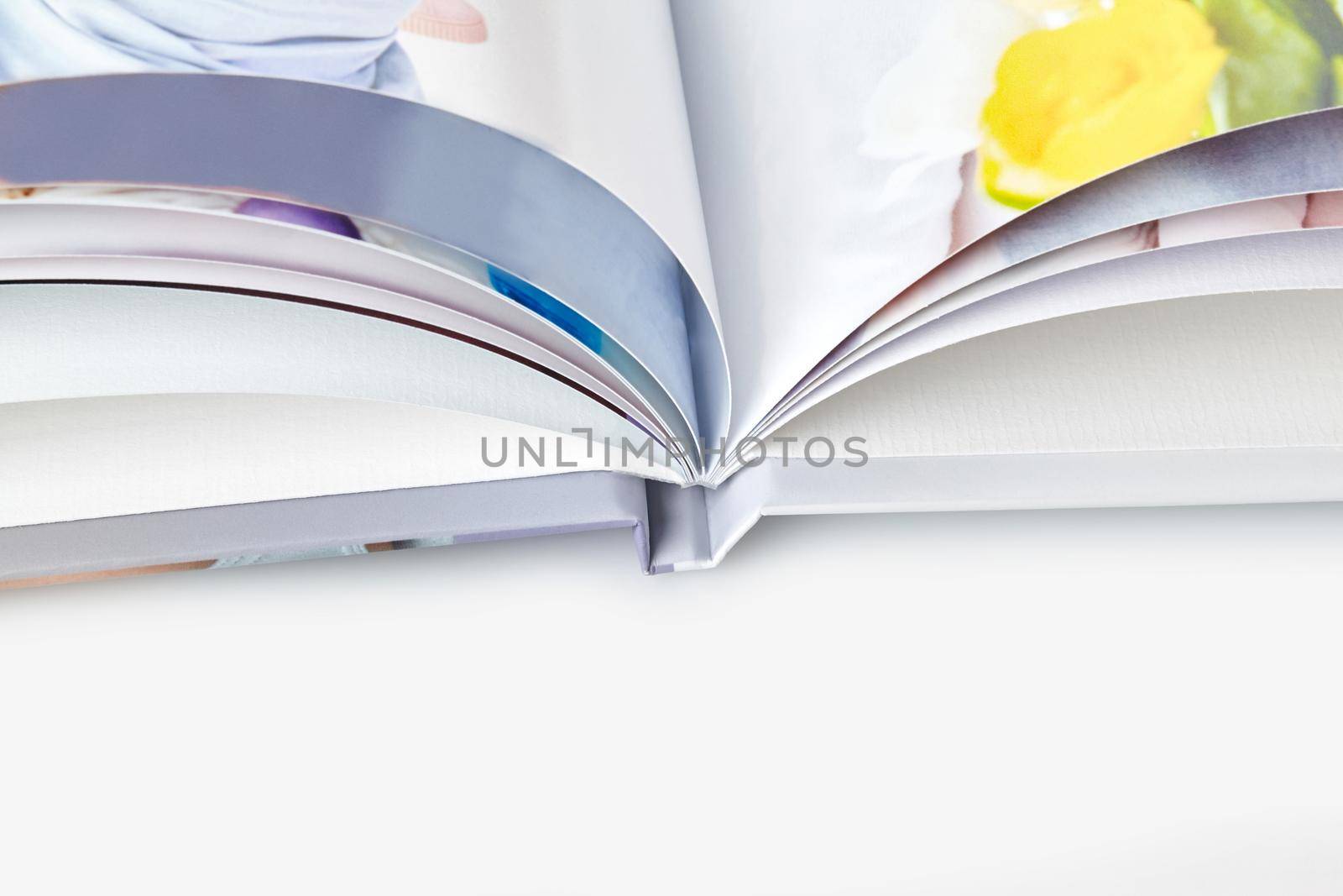 Open, high quality photo book with hardback and colorful pages on white studio background. Close up, copy space. Mock up, template