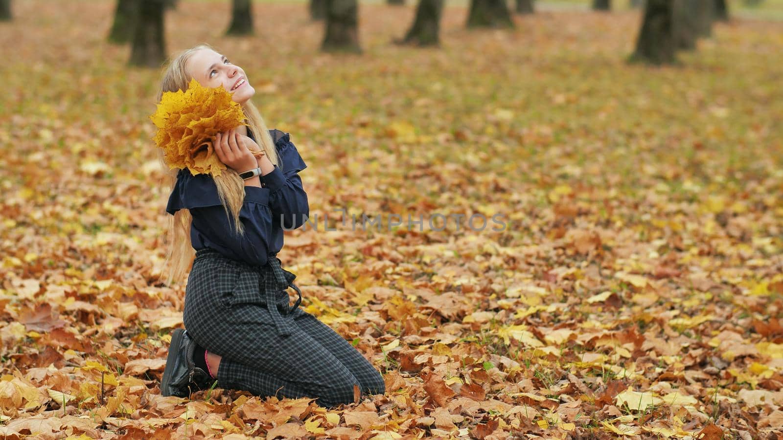 Teenager girl collects autumn leaves in the park and posing. by DovidPro