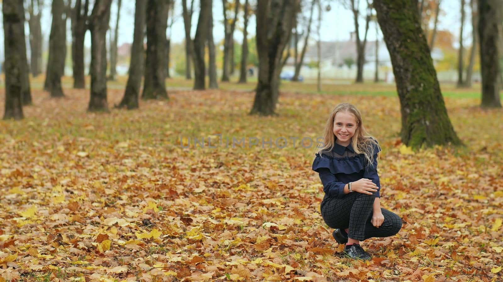 A teenage girl is sitting in an autumn park