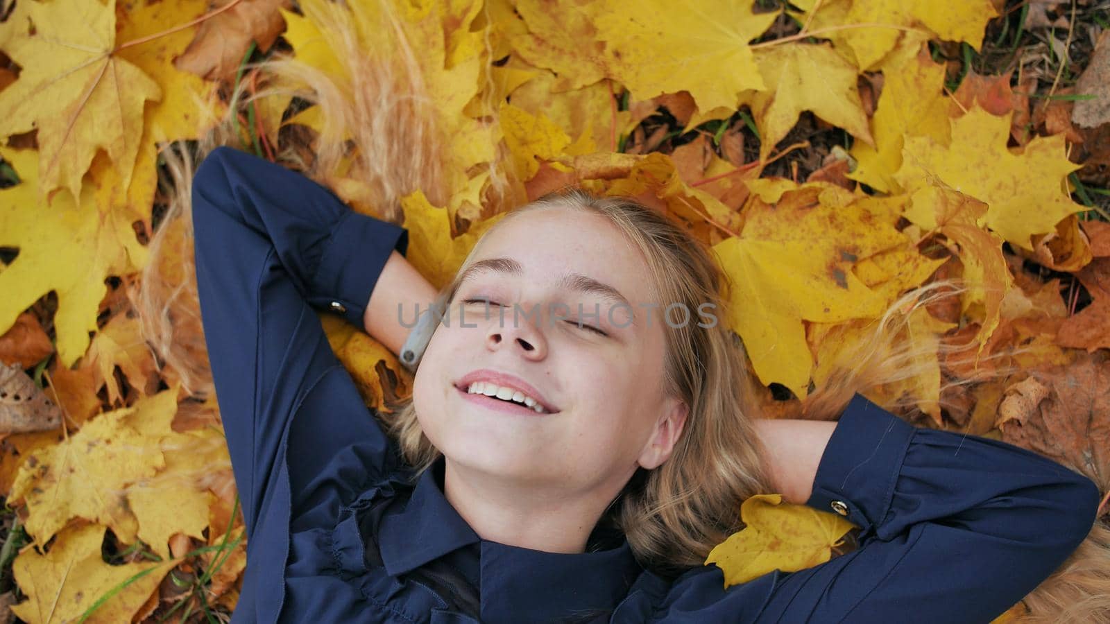 A young happy girl lies in the autumn leaves