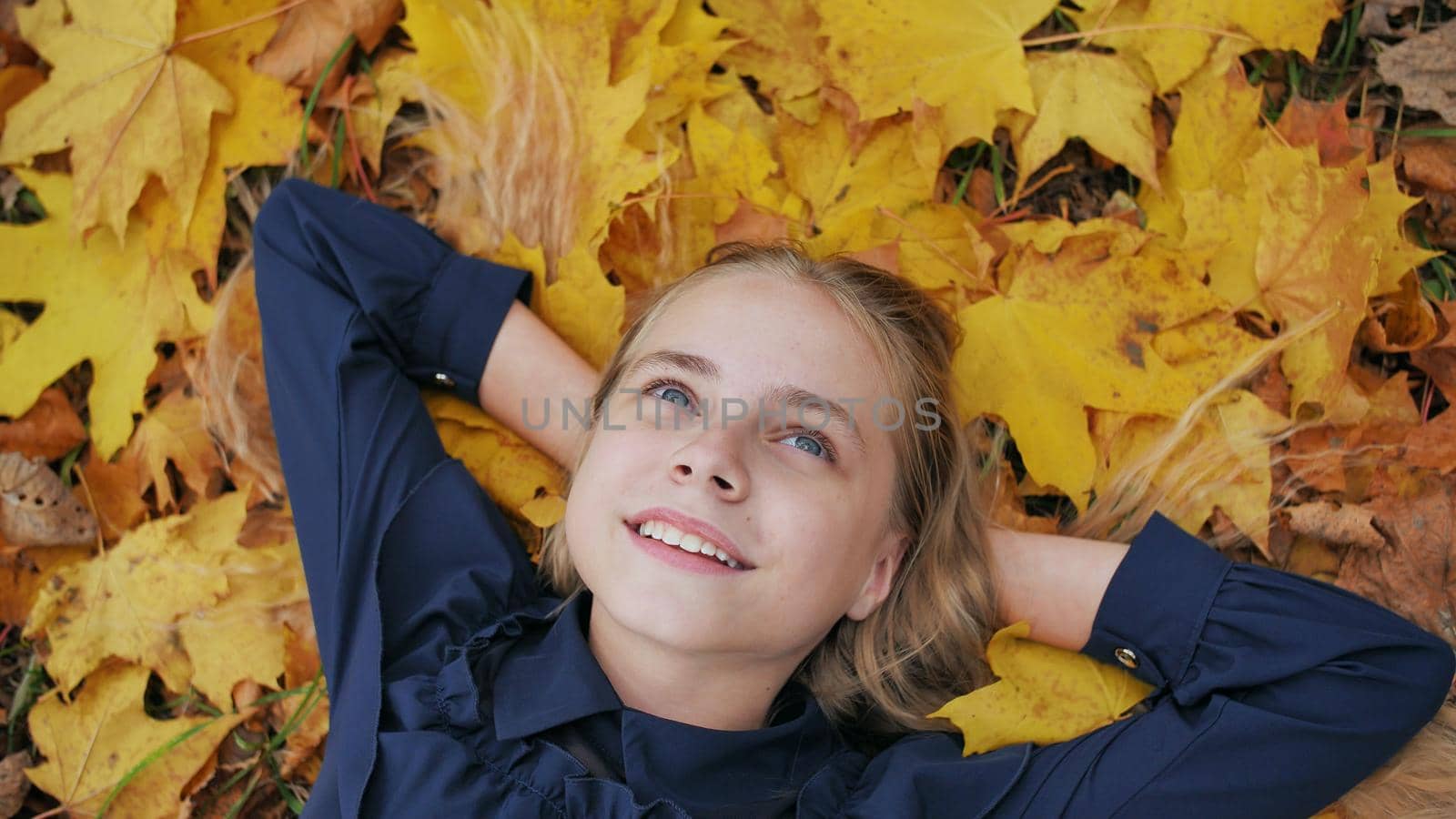 A young happy girl lies in the autumn leaves