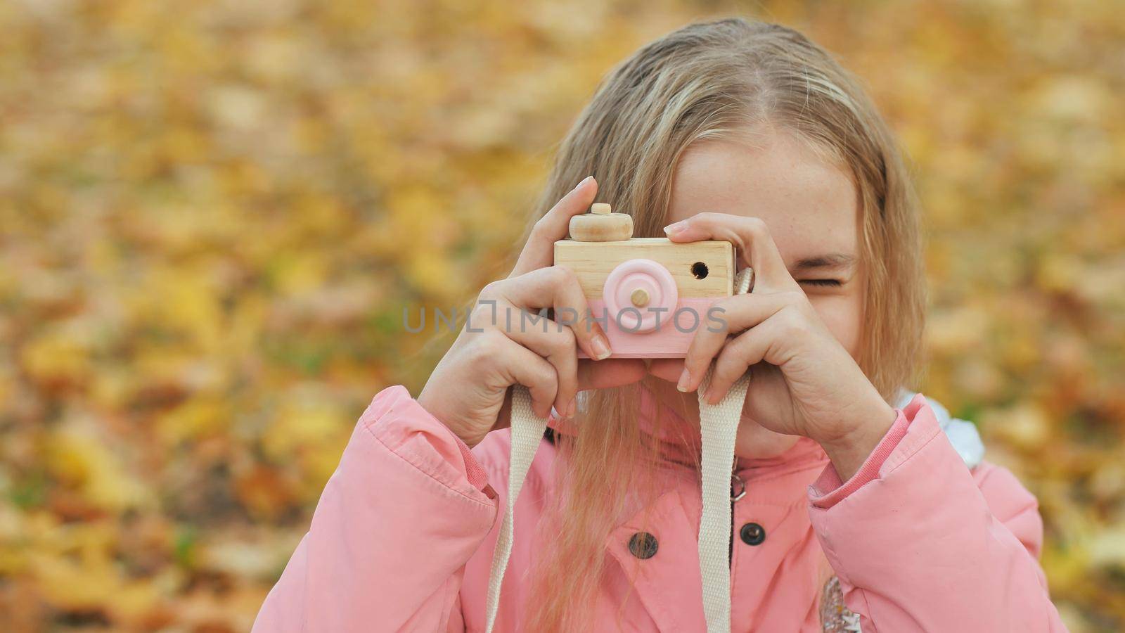 Teenage girl with toy cameras takes pictures in the autumn park. by DovidPro
