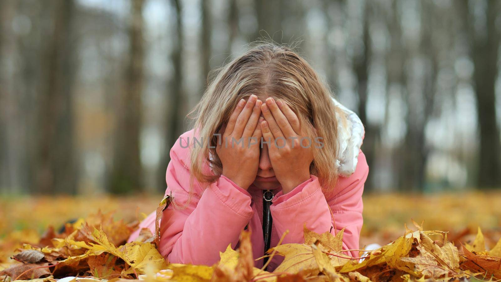 Teenage girl crying in the autumn foliage in the park. by DovidPro