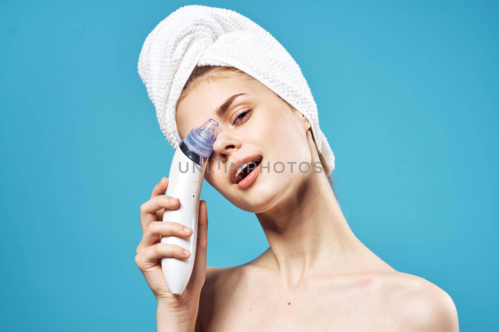 cheerful woman with a towel on her head massagers in hands dermatology clean skin by SHOTPRIME