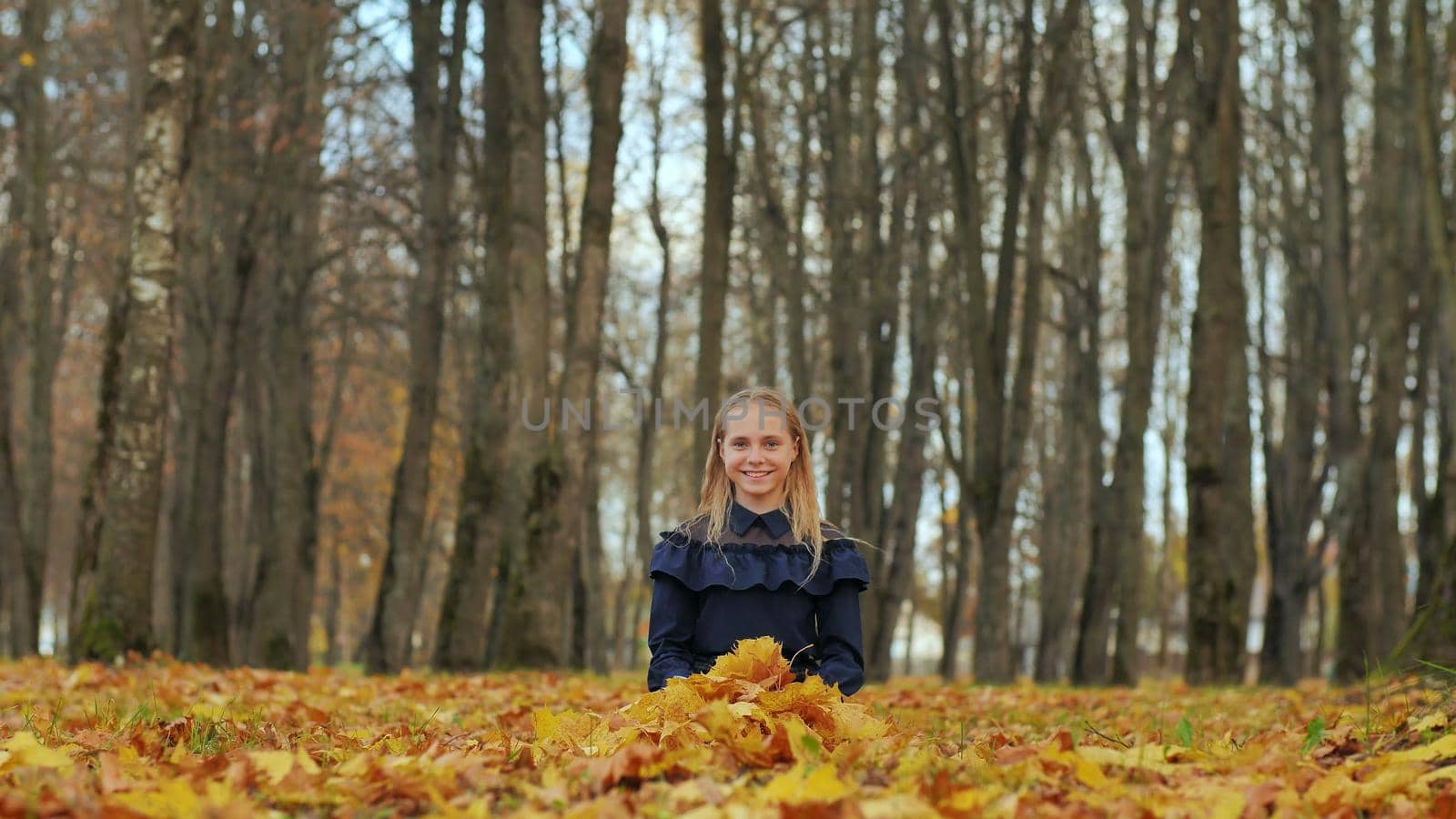 A teenage girl is sitting in an autumn park. by DovidPro