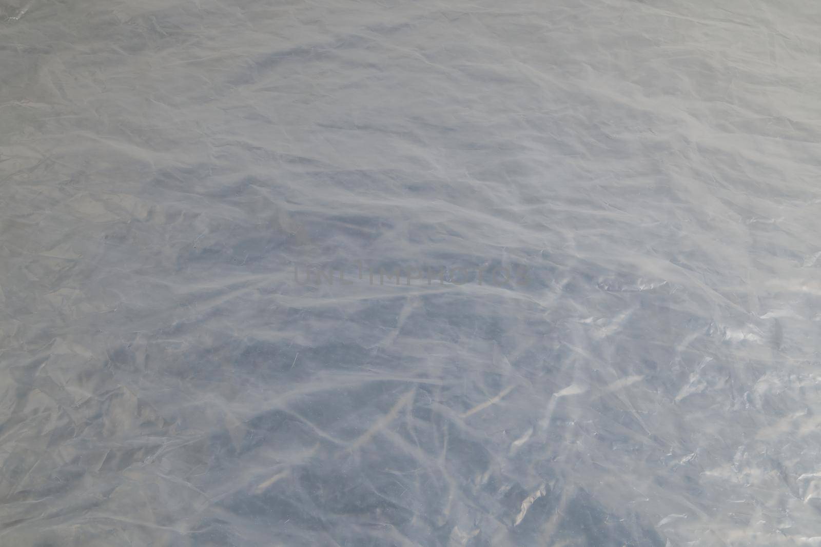 full frame background of flat crumpled semi-transparent polyethylene film.