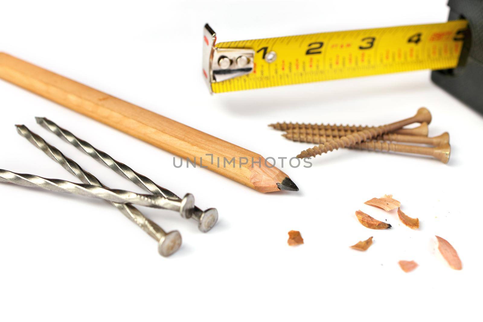 Low Angle Close up of a Carpenter's Pencil with Sharpening Shavings, Tape Measure, Framing Nails and Deck Screws on a white background. High quality photo