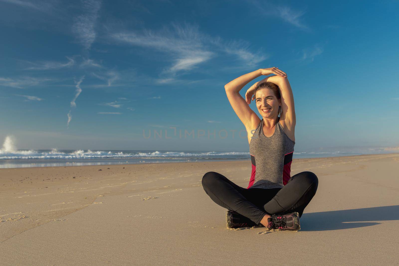 Shoot of a beautiful woman making stretching exercises in the beach