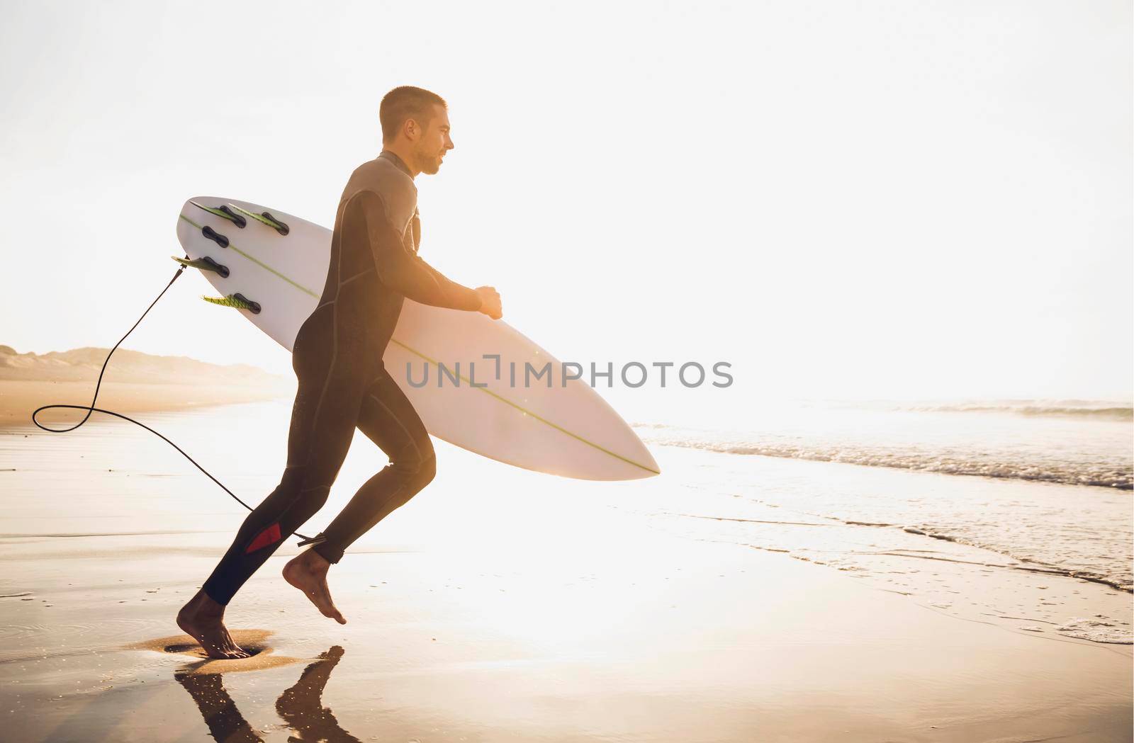 A surfer with his surfboard running to the waves