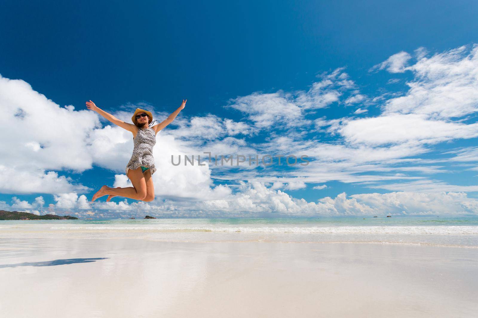 Beautiful woman jumping on the wonderful beach of Praslin, Seychelles