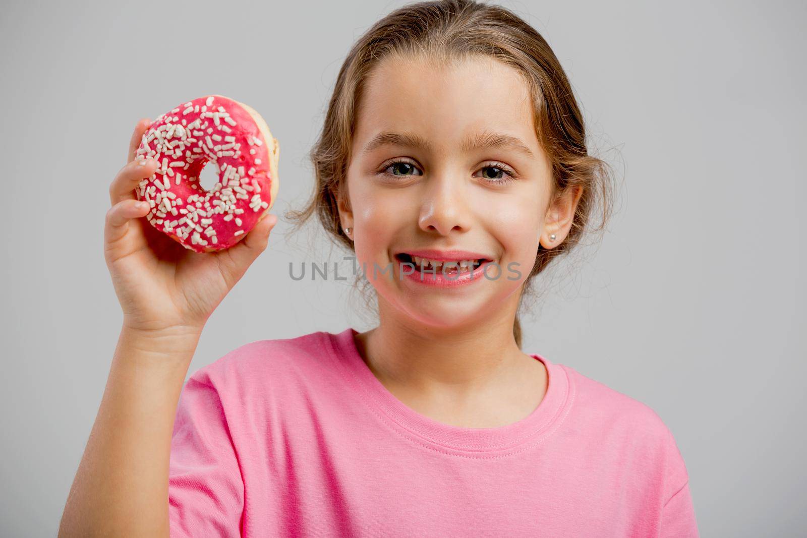 Studio portrait of a beautiful little girl holding a donut