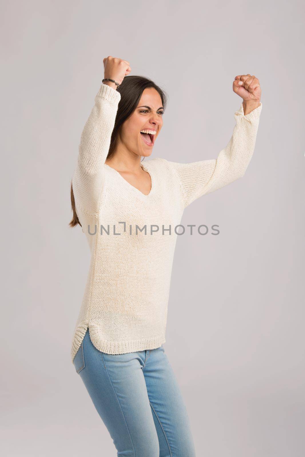 Studio shot of a happy young woman with arms raised
