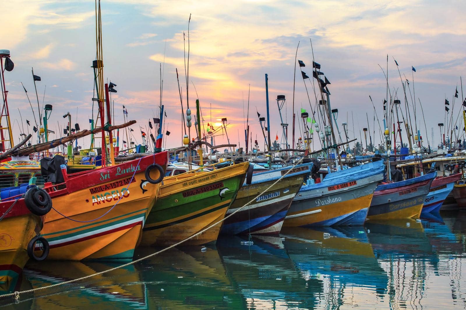 Mirissa, Sri Lanka - April 14, 2017: Colorful boats in Mirissa port with morning sun rising in the background.