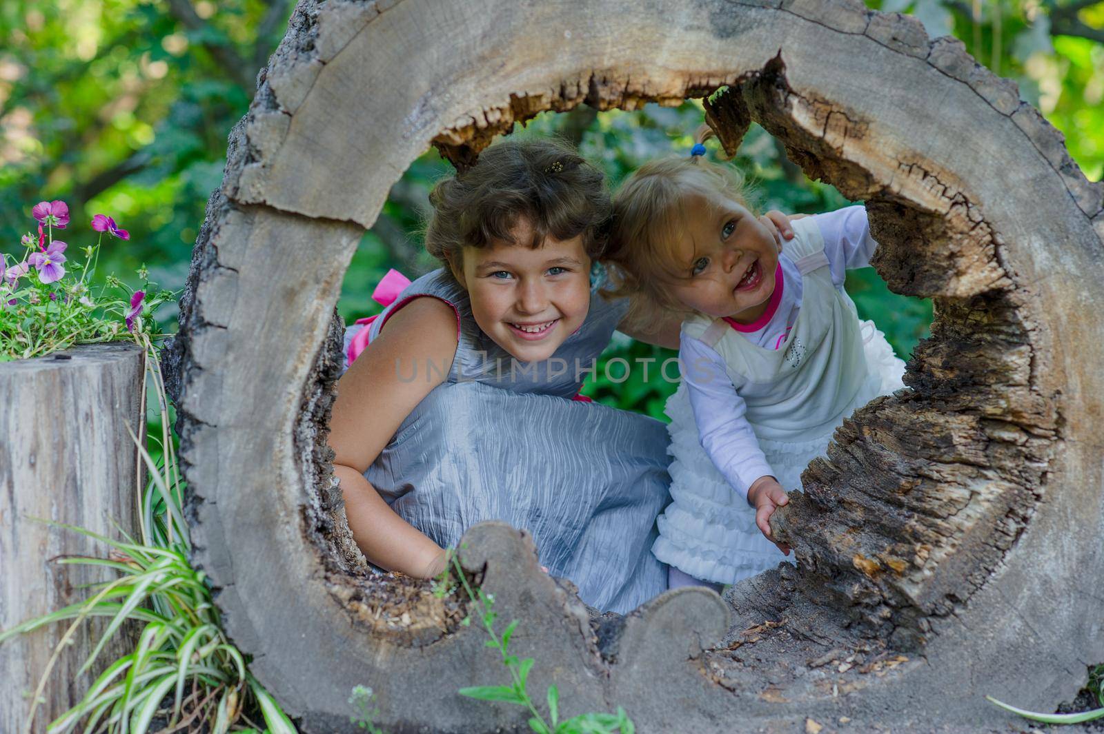 Two funny little girls having fun with a sleigh in beautiful park. High quality photo