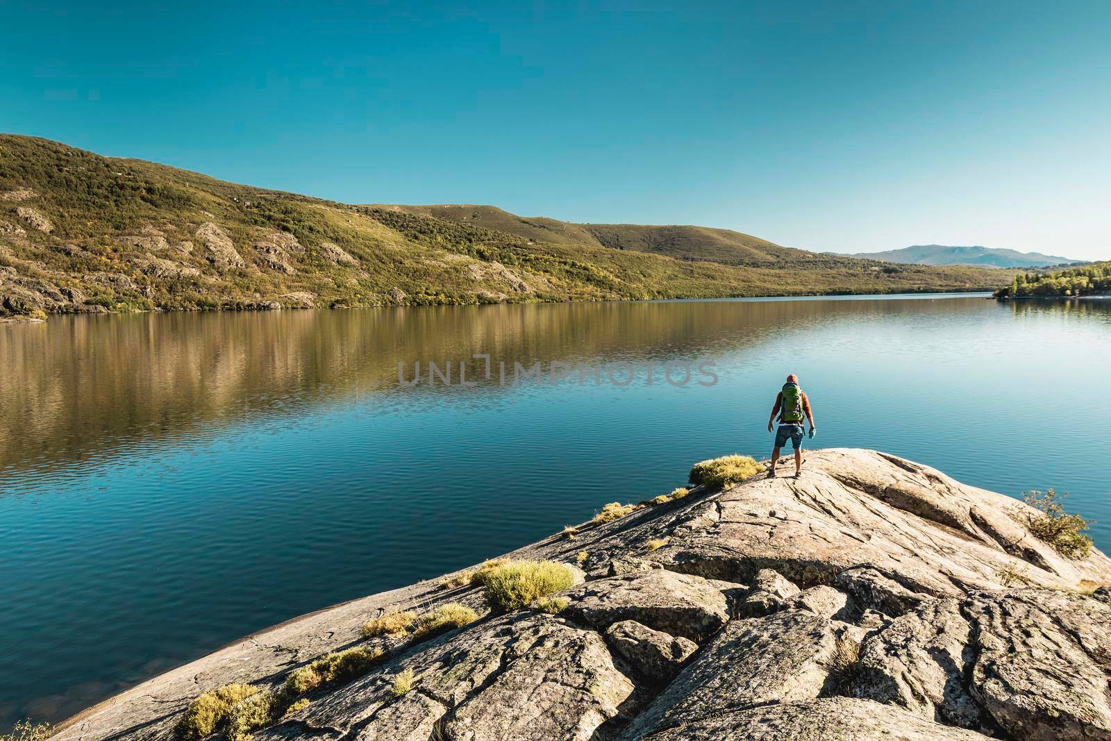 Man hiking near a beautiful lake by Iko