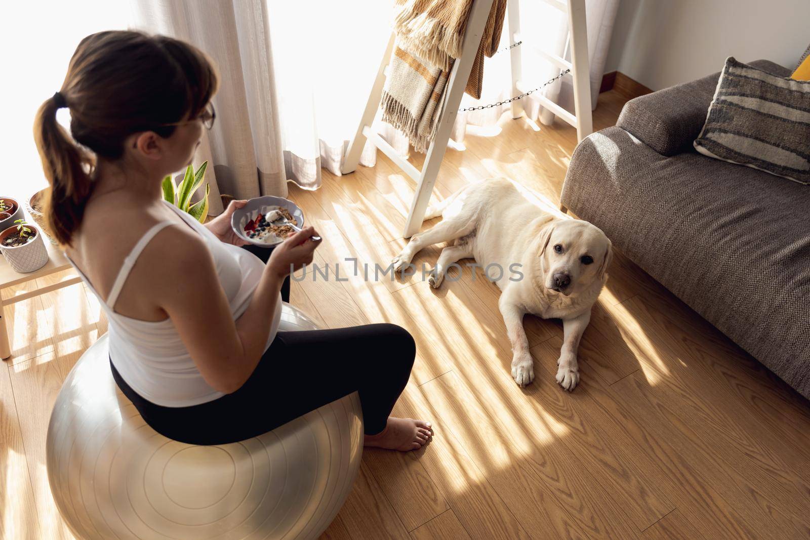 Pregnant woman working at home resting and eating healthy food in the company of her best friend