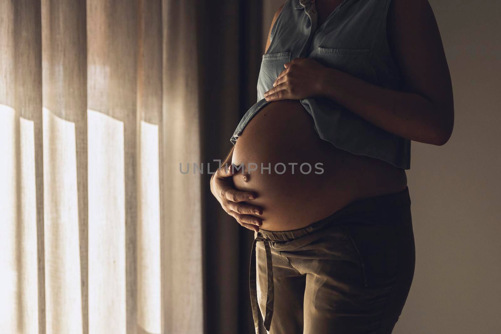 Pregnant woman touching her belly by the morning