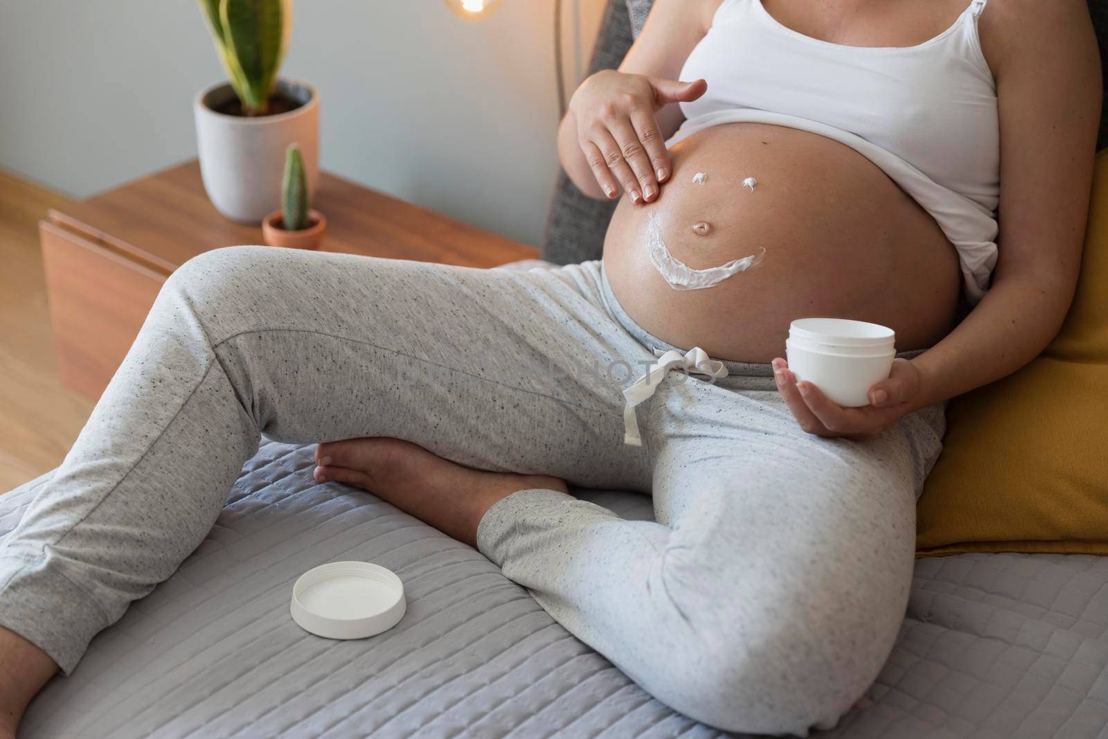 Pregnant woman applying stretch mark cream in her belly