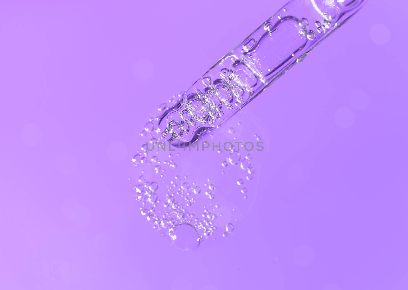 Pipette with fluid hyaluronic acid on violet background. Cosmetics and healthcare concept closeup. Dose of serum or retinol with air bubbles. Flat lay. Luxury beauty product presentation in macro