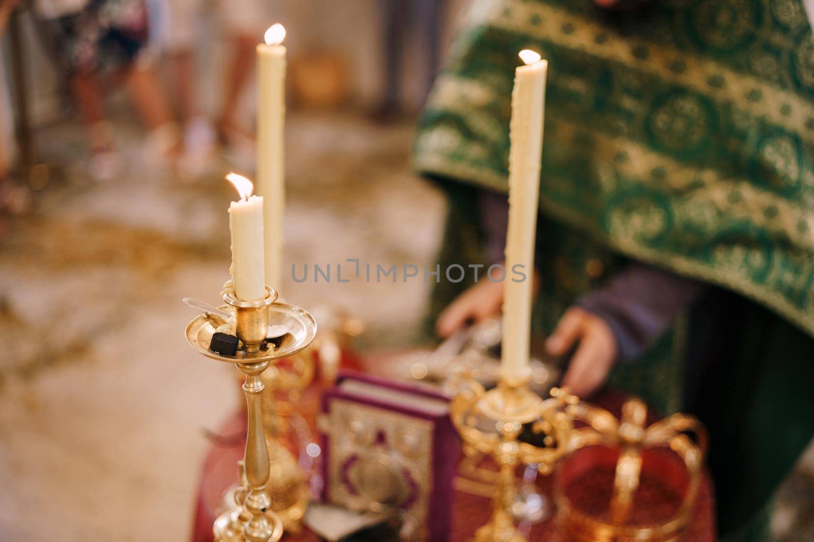 Candles are burning on candlesticks in front of the priest in the church. High quality photo