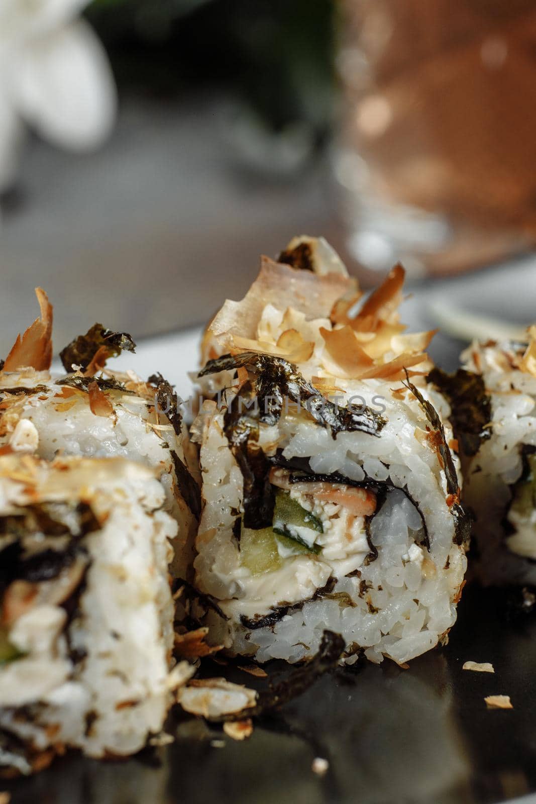 Golden dragon sushi roll with tuna, eel, cucumber, sesame seeds and tobiko caviar on wood background.