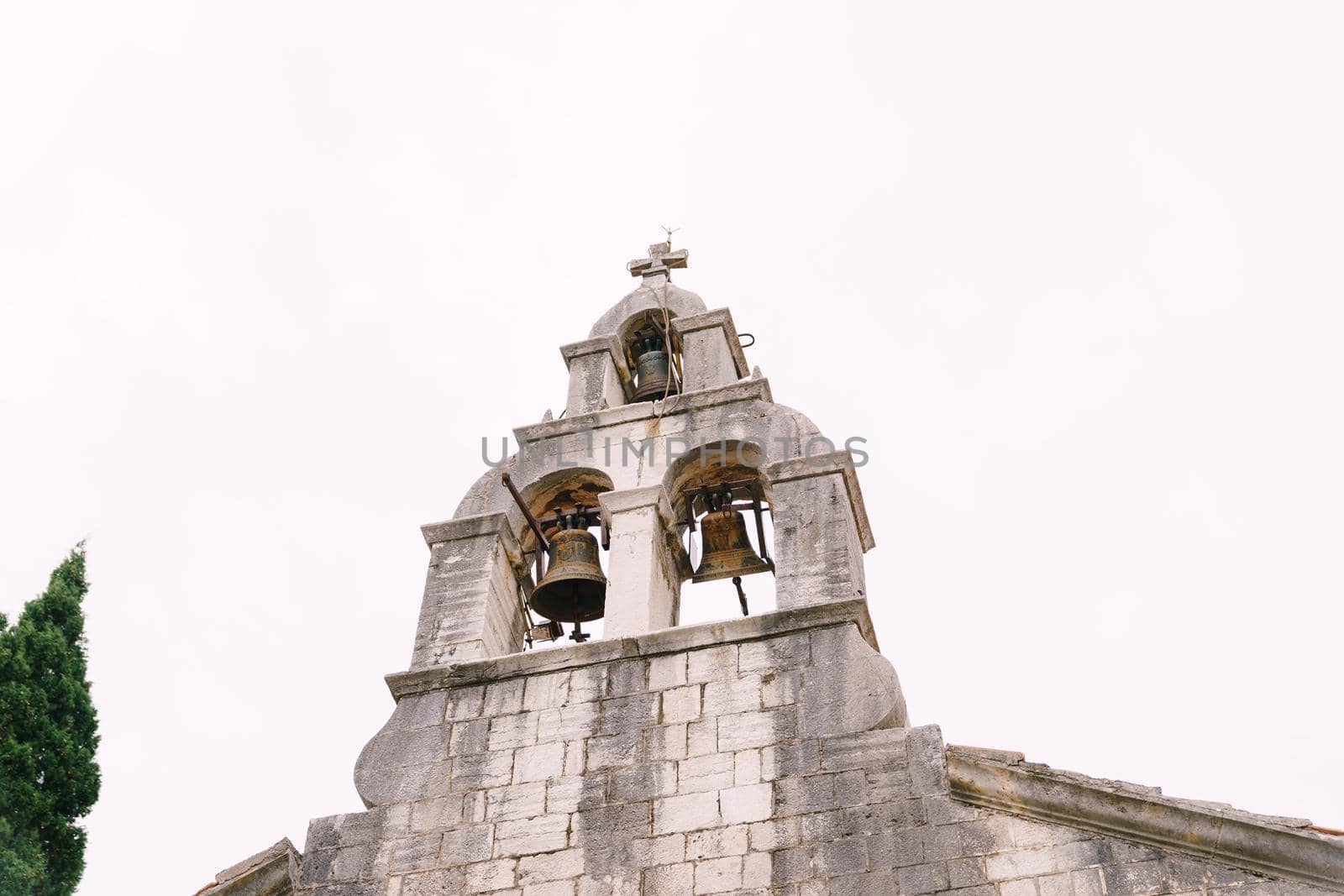 Stone bell tower with three bells against the sky. High quality photo