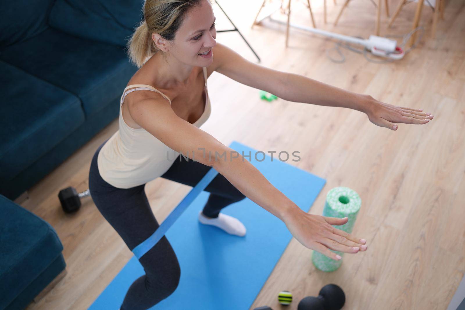 Woman with elastic band on her legs doing squats, close-up. Stretching and aerobics at home during a pandemic