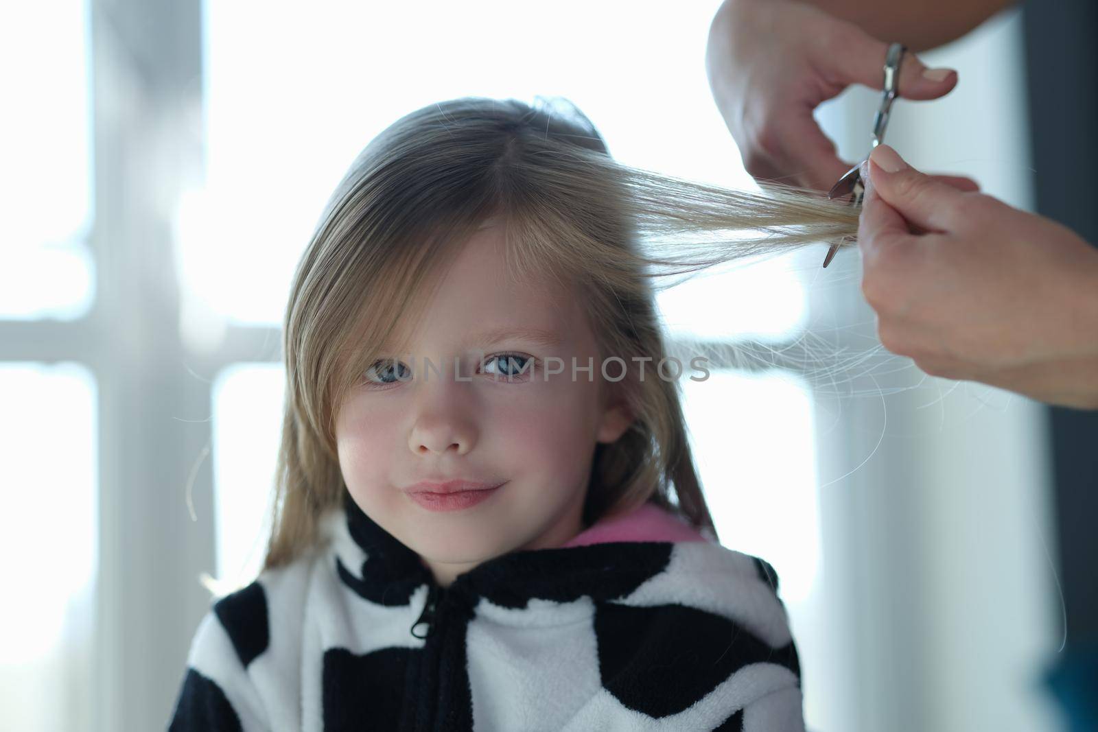 Sweet little girl cutting a lock of hair by kuprevich