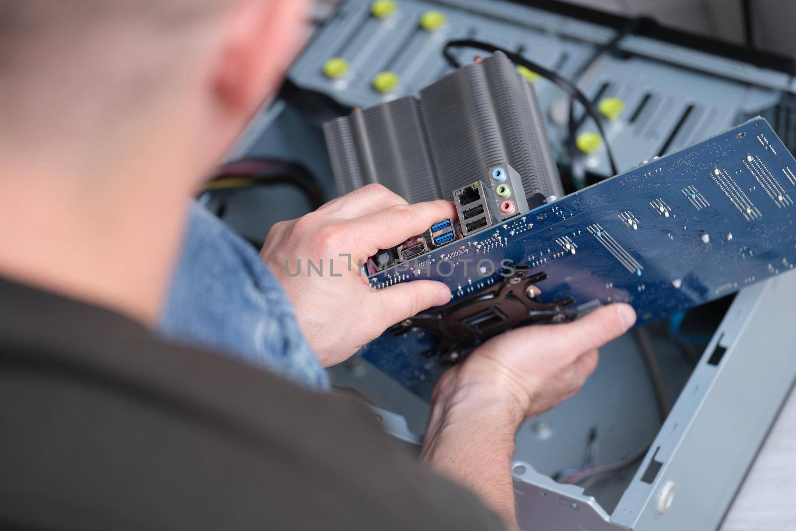 The man took out the motherboard from the computer, close-up. Processor repair and pc heatsink replacement