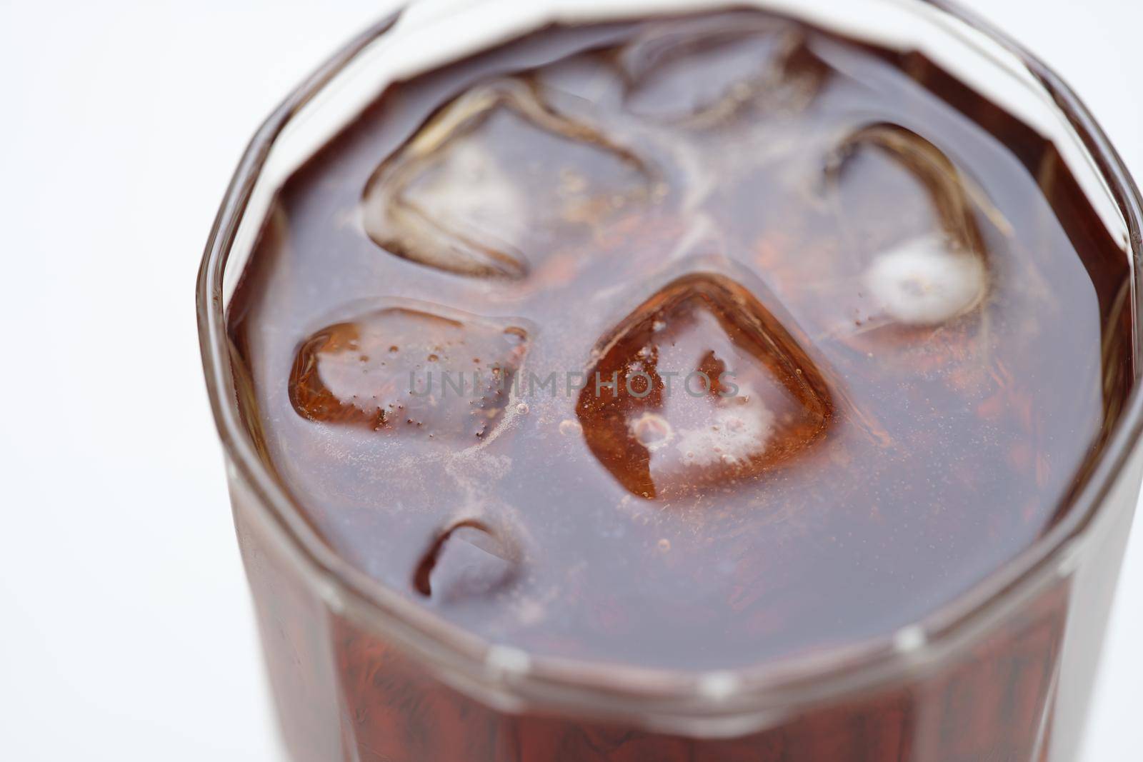 Close-up top view of brown drink with ice. Alcoholic cocktail with cola on a gray background. Cold refreshing soft drink