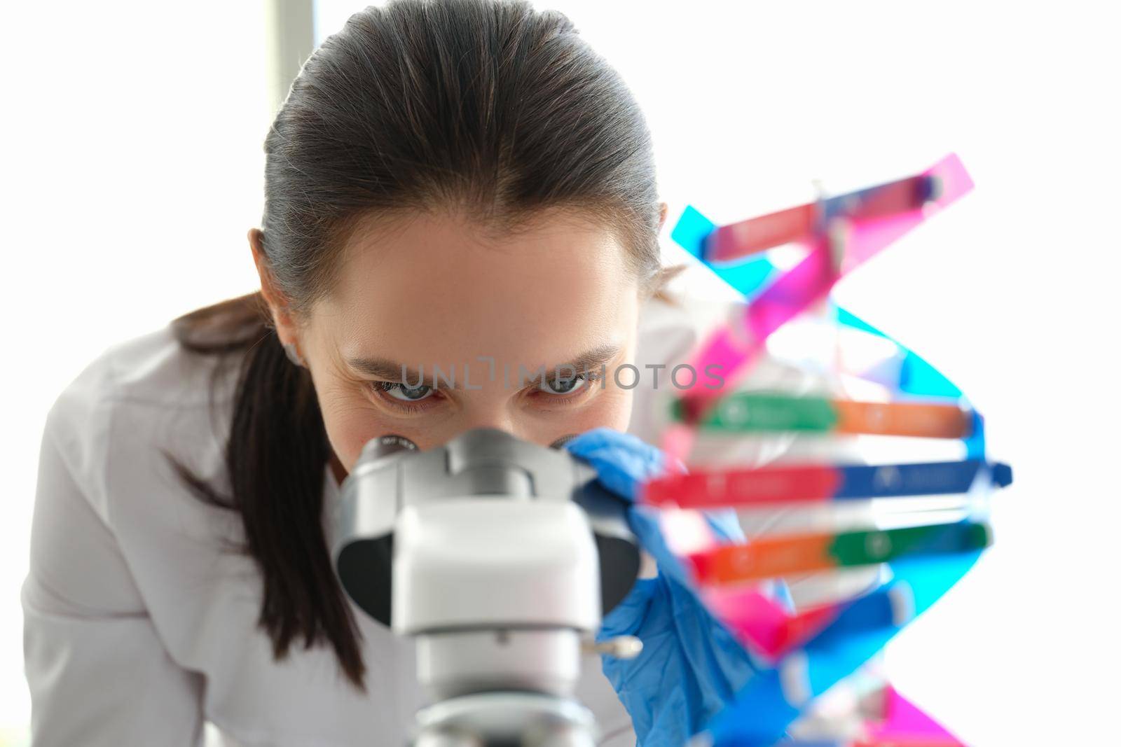 A woman biologist looks through a microscope close-up. DNA sample. Genetics research. Pharmaceutical laboratory