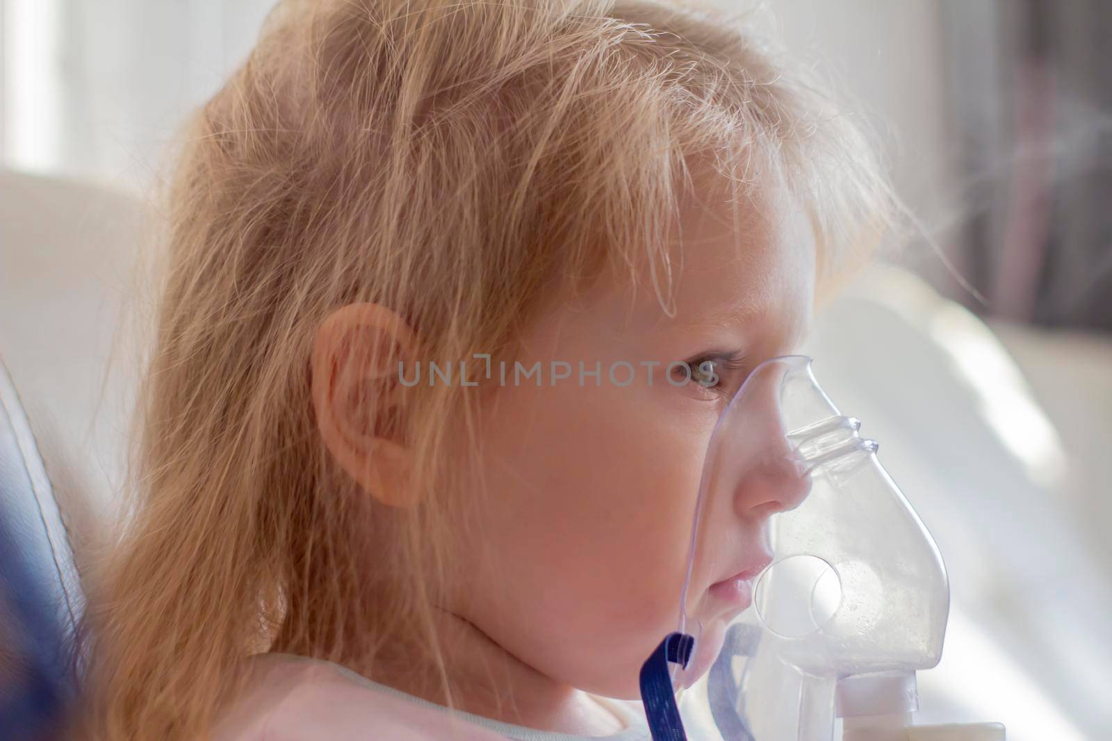 Little girl having inhalation for easing cough. Caucasian blonde girl inhales couples containing medication to stop coughing. Medical procedures. Inhaler. Respiratory medicine.