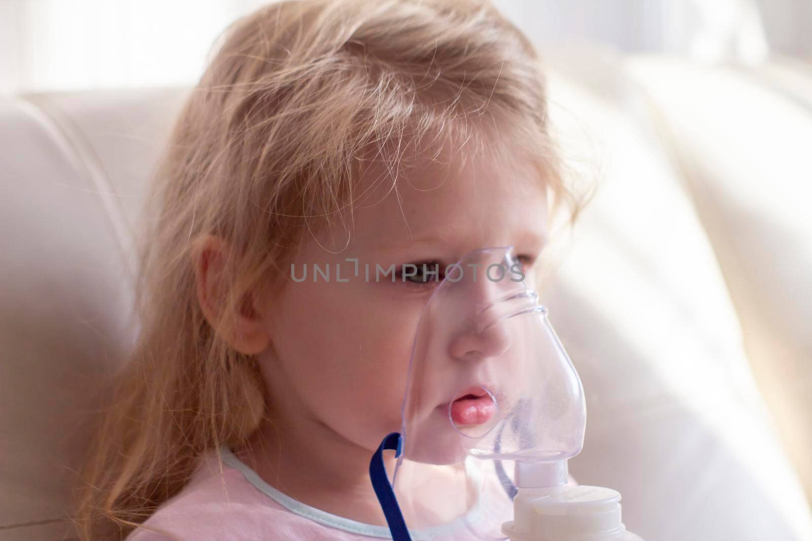 Little girl having inhalation for easing cough. Caucasian blonde girl inhales couples containing medication to stop coughing. Medical procedures. Inhaler. Respiratory medicine.