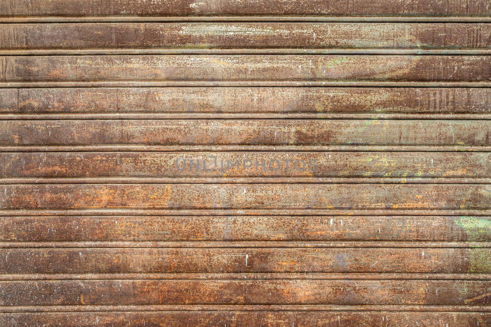 Metal shutter with peeling paint. Front view of a shutter rusted, deteriorated from elements. Ideal use for background, wallpaper.