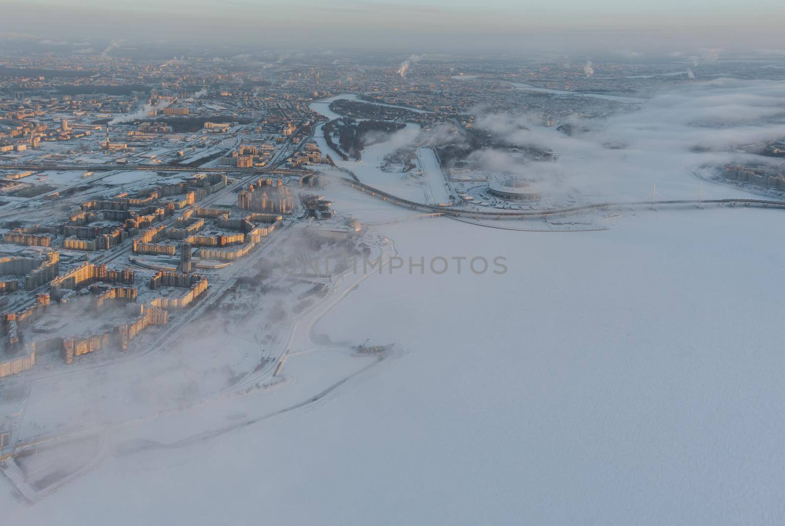 Russia, St. Petersburg, 08 January 2022: Snow-covered stadium Gazprom Arena near the expressway on a winter frosty evening, view from drone to the embankment. High quality photo