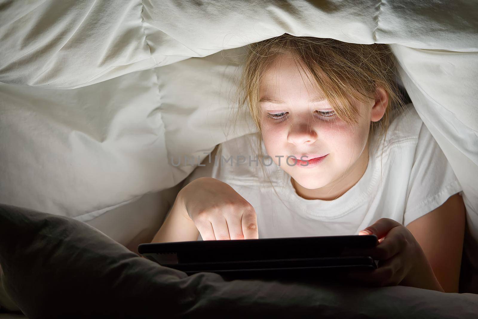 Gadget night. Romantic chat. Late home leisure. Online communication. Portrait of girl with mobile phone under blanket at night. cyber bullying