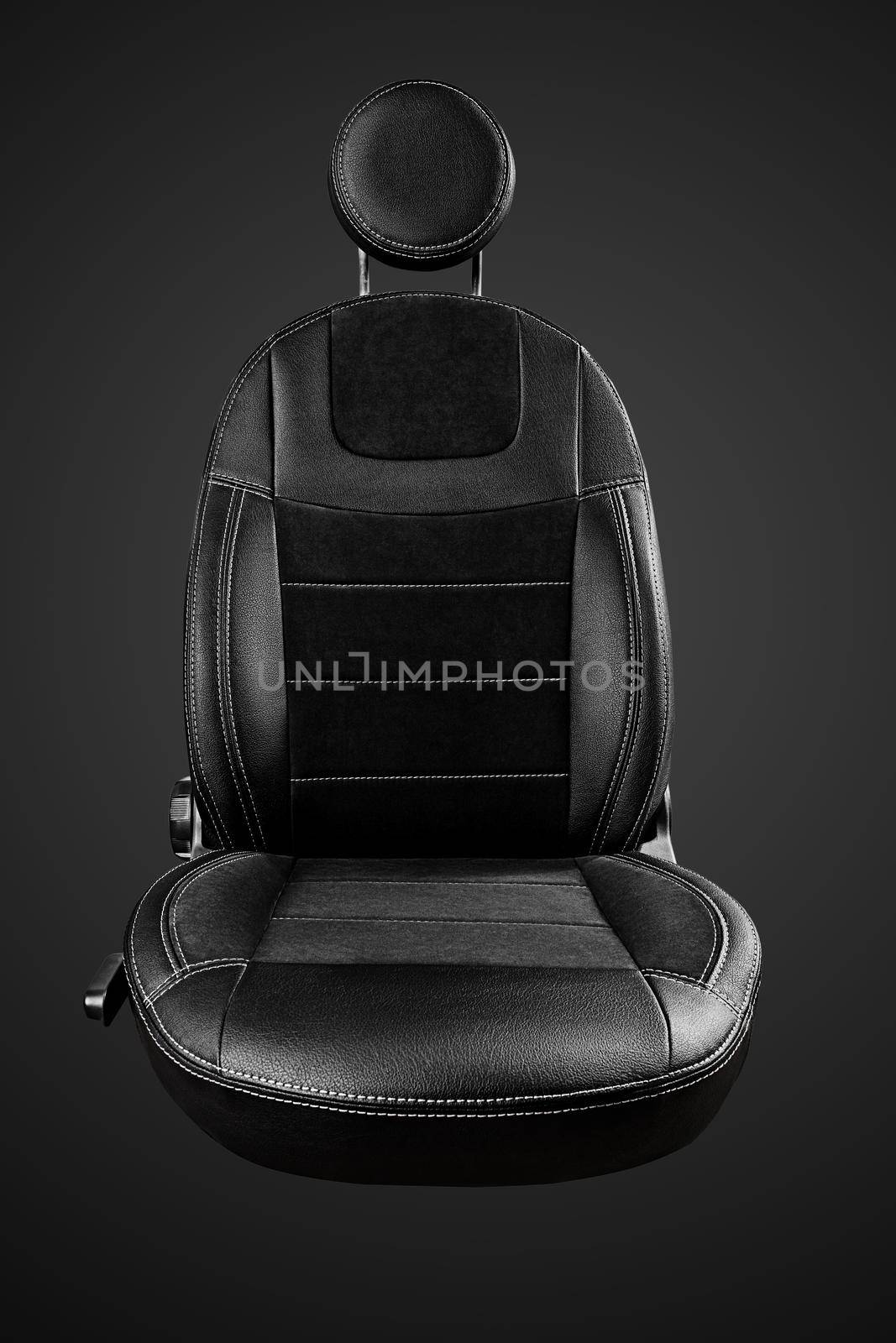 Comfortable driver car seat with round headrest in faux leather with suede inserts isolated on black background, front view