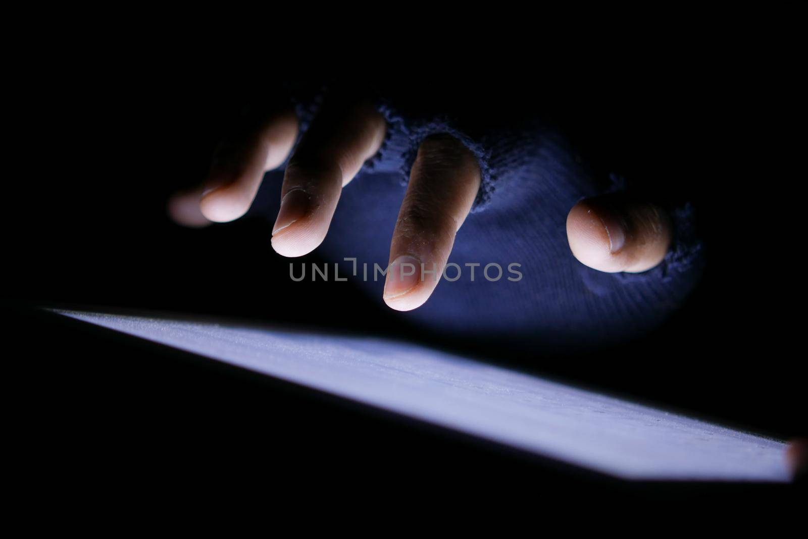Close up of hacker hand stealing data from digital tablet.