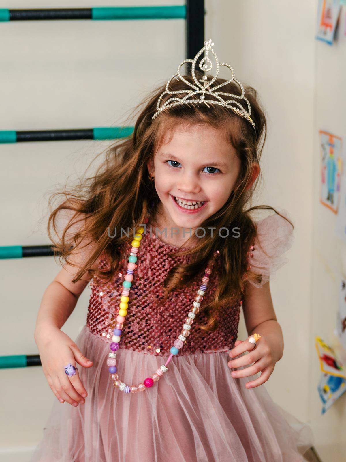 a little girl in a beautiful dress and crown plays and runs around the house, close-up.