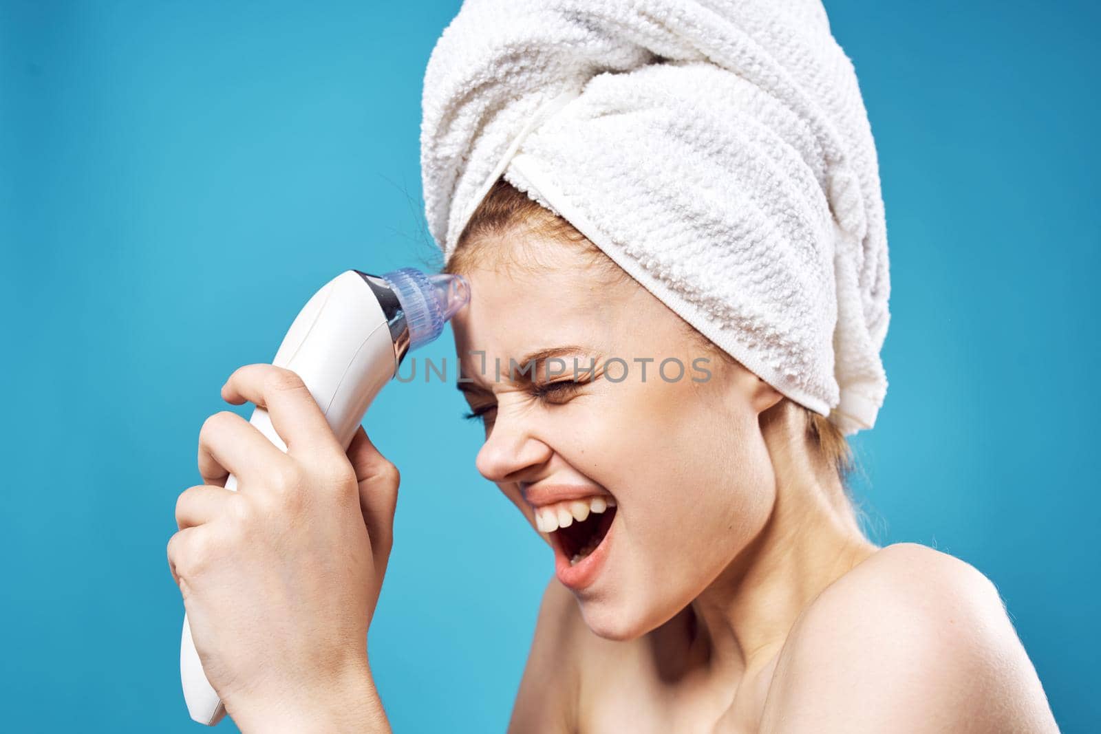 woman with towel on head cleaning face skin care blue background by SHOTPRIME